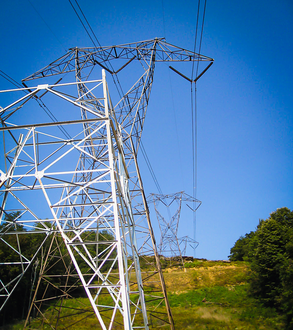 Transmission towers on a grassy hill
