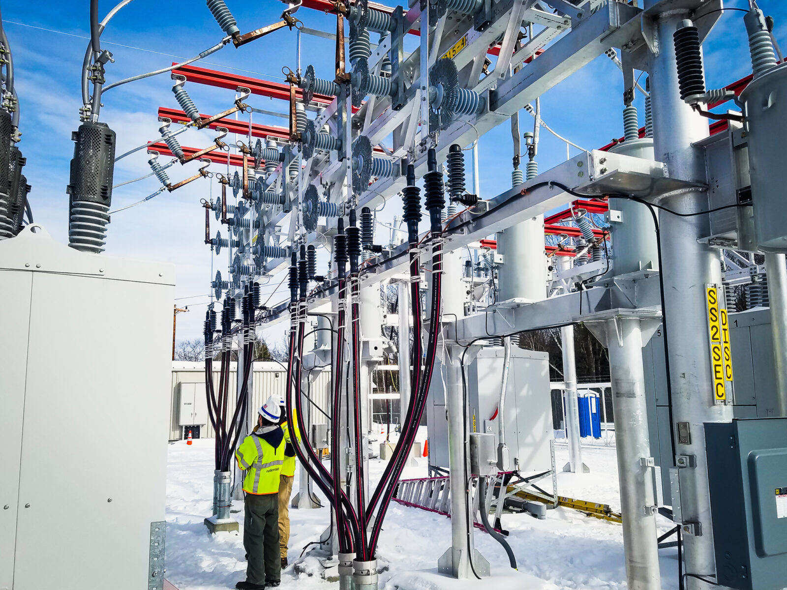 Two workers in a snowy substation