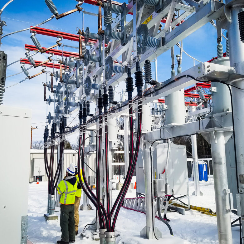 Two workers in a snowy substation