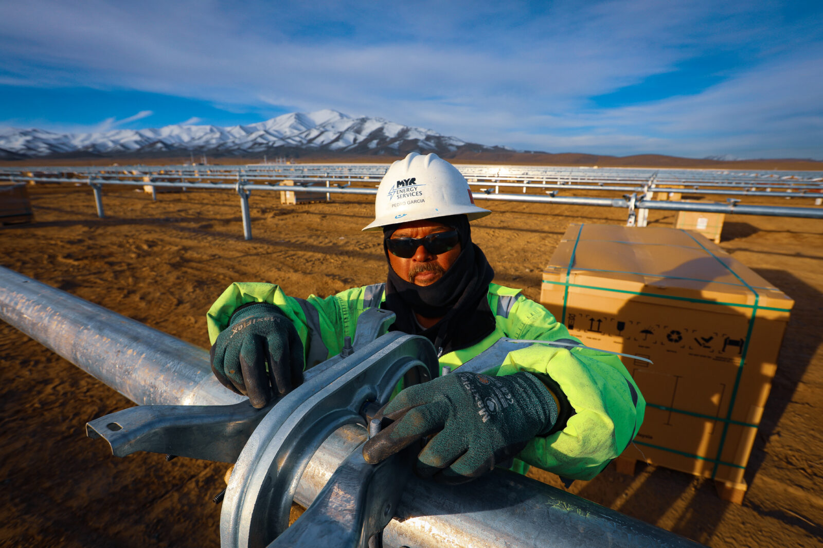 MYRE Energy employee prepares for solar panel installation with snowcapped mountains in the distance