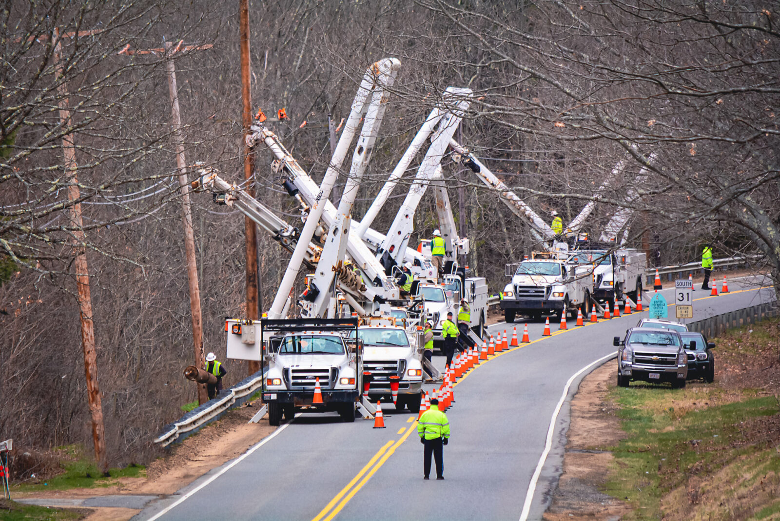Row of white bucket trucks on a road