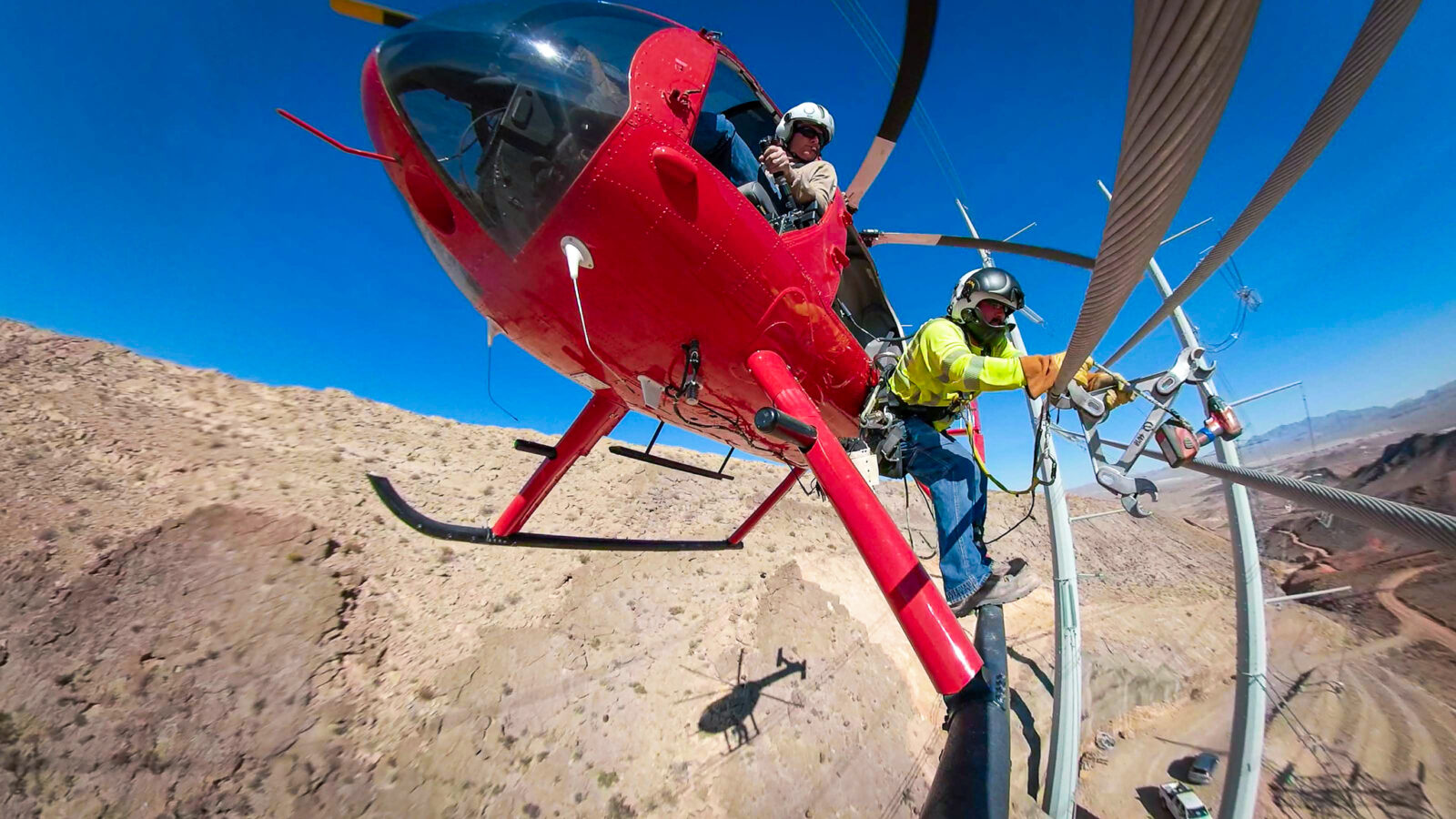 Two workers on a helicopter to reach and work on a power line