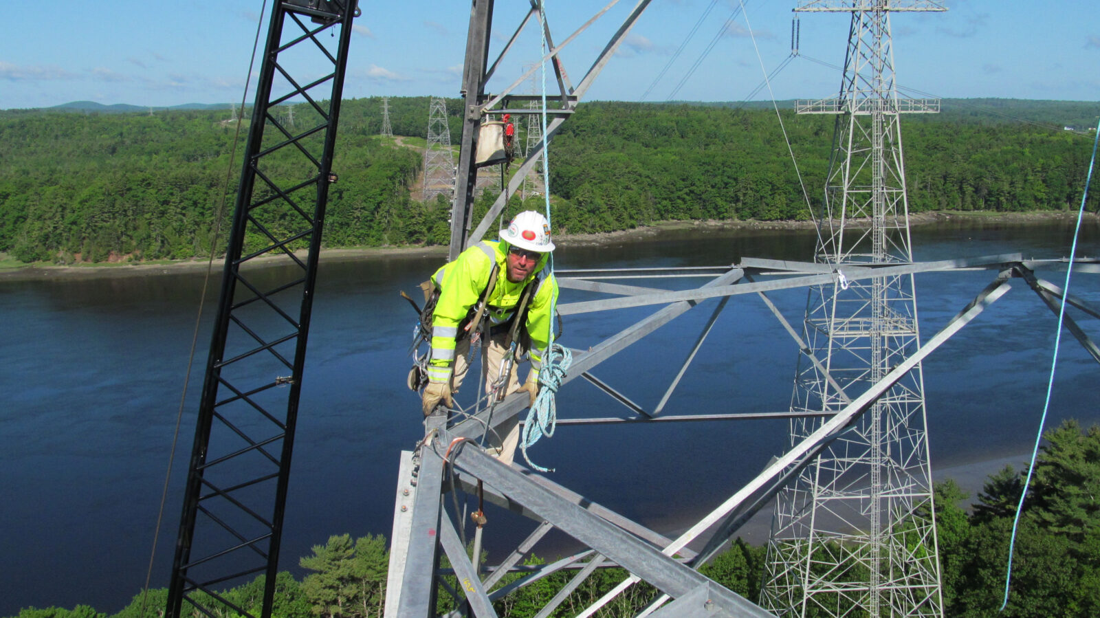 Worker crouched on the beam of a transmission tower