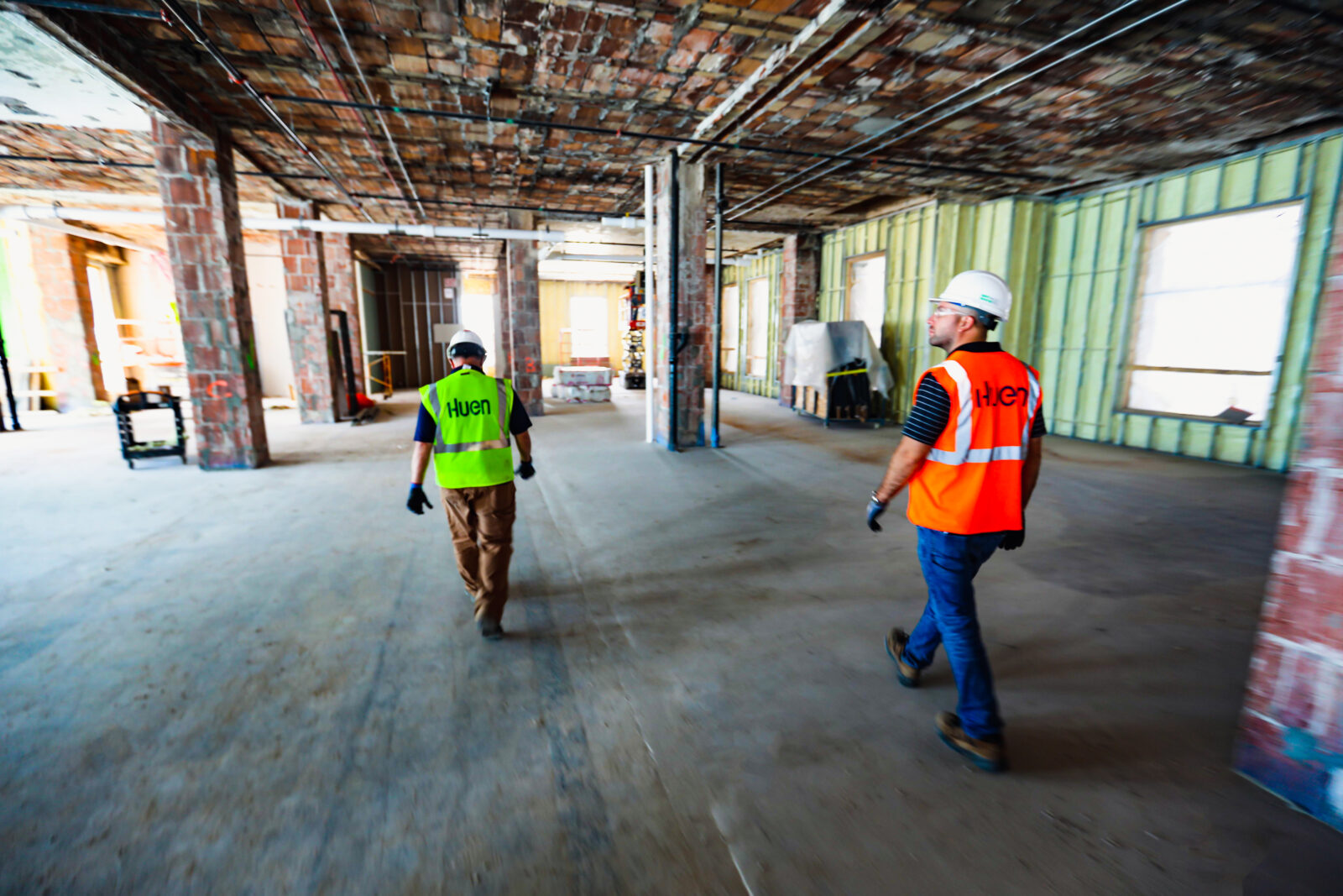 Two Huen workers walking in a large room during construction