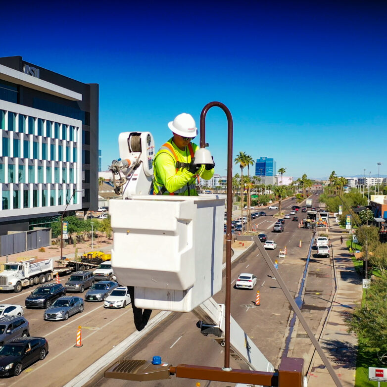 An electrical worker stands in a bucket truck while working on a streetlight