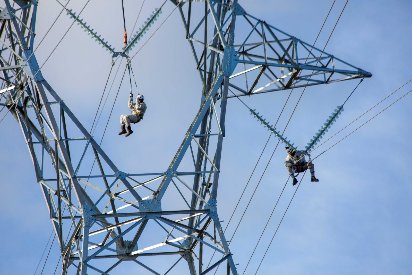 employees working on transmission line while hanging from harnesses