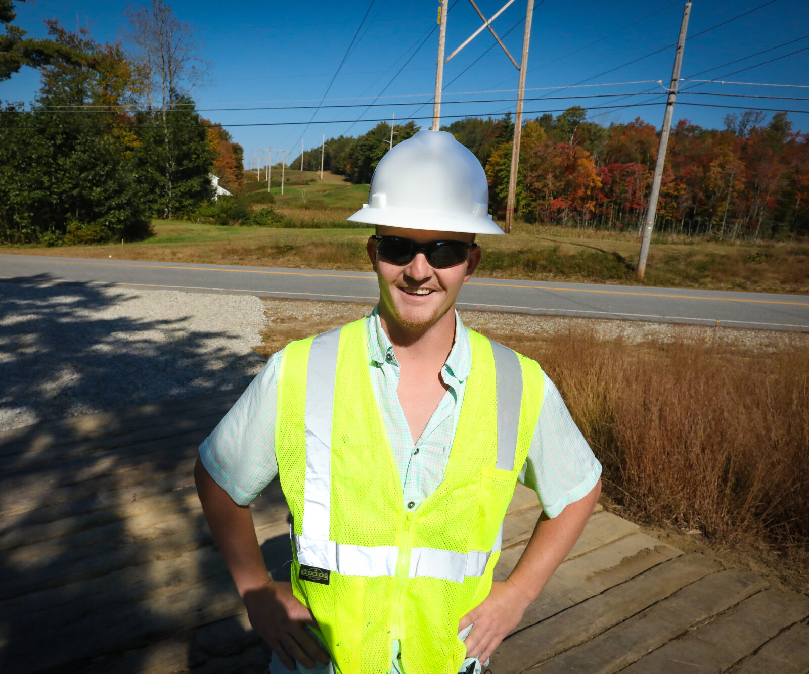 Construction crew member poses in front of power lines