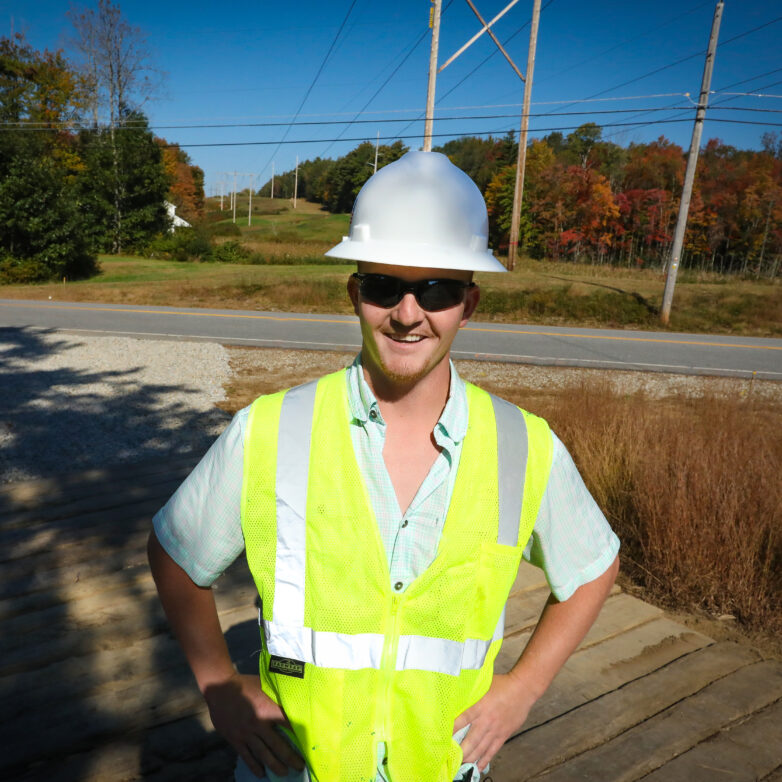 Construction crew member poses in front of power lines
