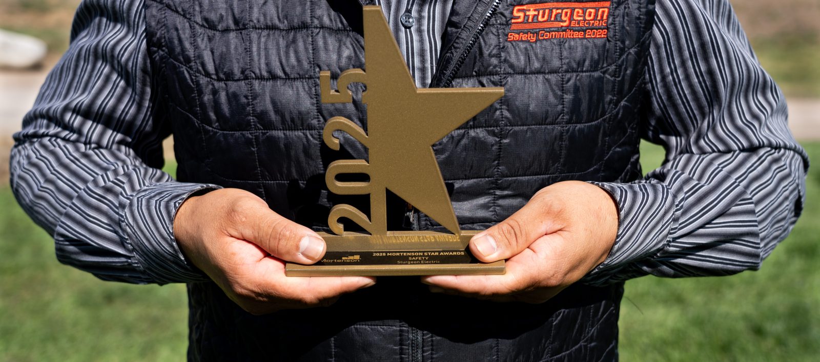 A man holds an star shaped award with 2025 on it.
