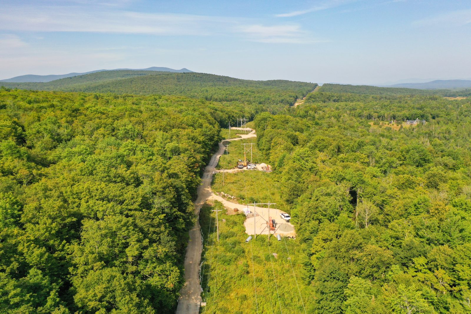 An aerial view of a transmission line stretching through a green forest.