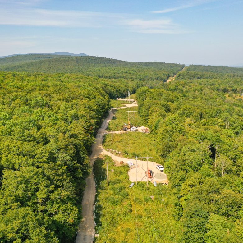 An aerial view of a transmission line stretching through a green forest.